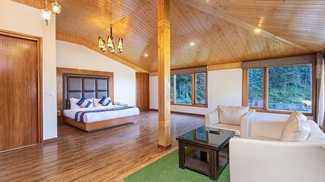 A spacious and luxurious hotel room with a king size bed, a sitting area, and large windows offering scenic views  | DLS Serenity Resort and Spa